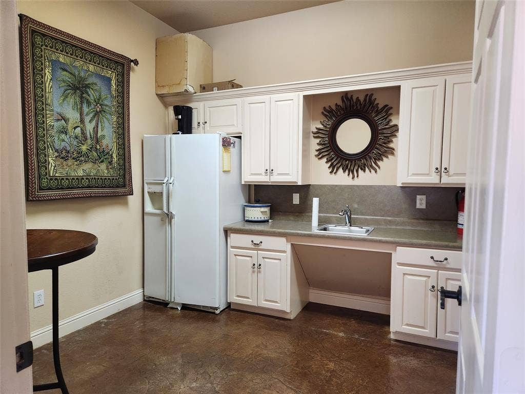 1905 W Ennis Avenue, #301, Ennis, TX 75119 Compact kitchen area featuring white cabinetry, a stainless steel sink, and durable concrete-finish flooring