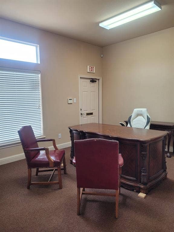 1905 W Ennis Avenue, #301, Ennis, TX 75119 Spacious room featuring a decorative wood-finish desk, neutral wall paint, and a large window with horizontal blinds