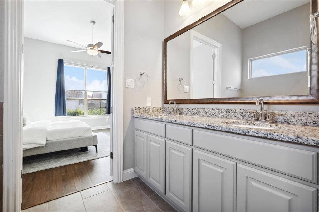 Bathroom vanity featuring a dual sink, granite countertop, and light gray cabinetry
