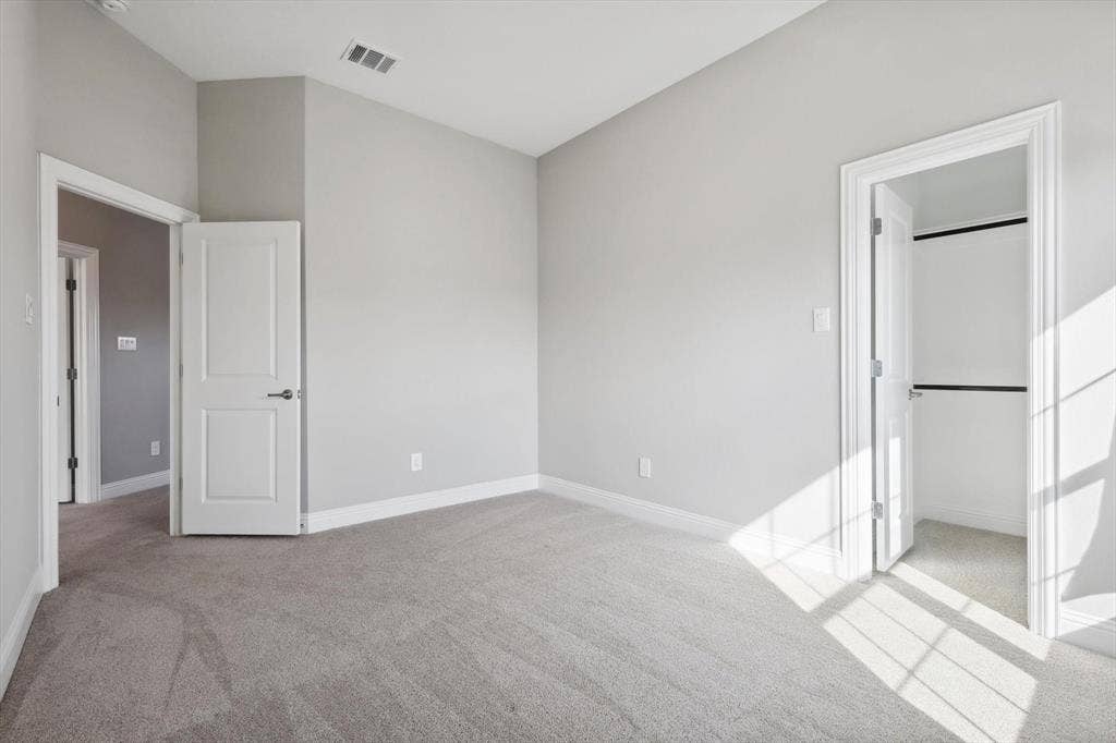 Carpeted room featuring light gray walls, white baseboards, and a contemporary ceiling vent