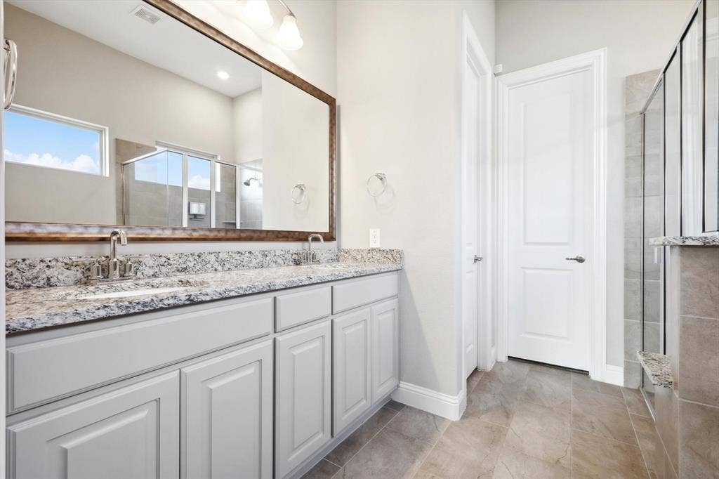 Bathroom vanity featuring dual undermount sinks with brushed nickel faucets, granite countertop, and light gray cabinetry