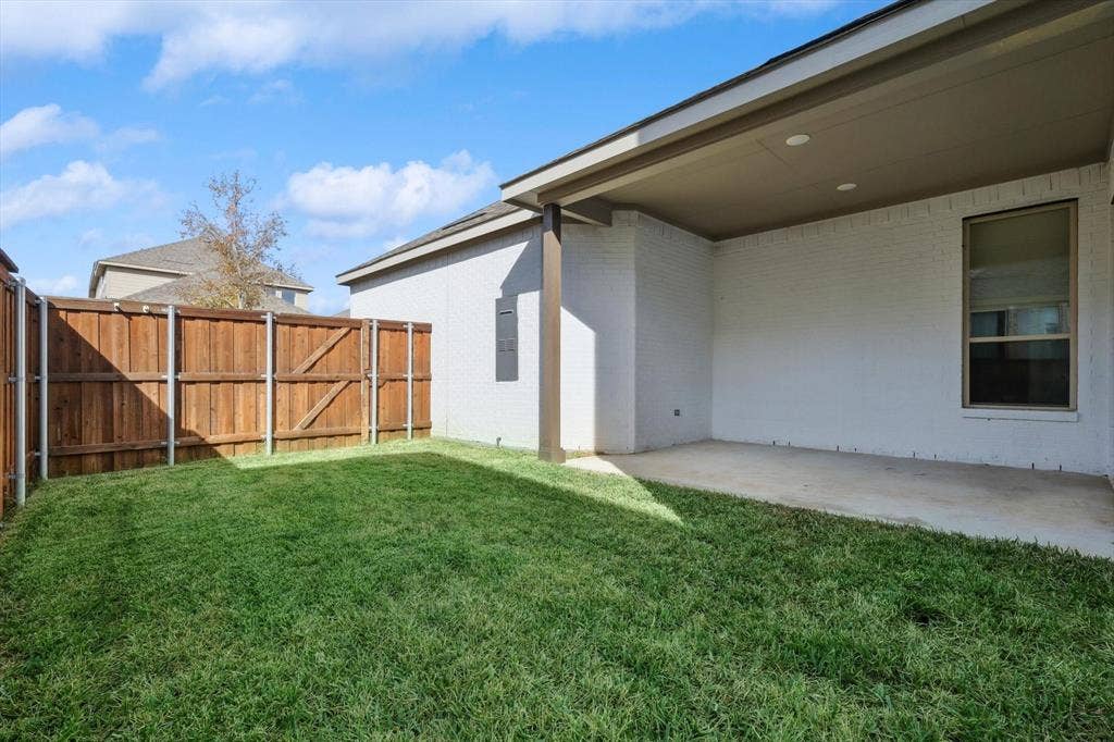 Backyard featuring a covered patio with recessed lighting, concrete flooring, a manicured lawn, and wood privacy fencing