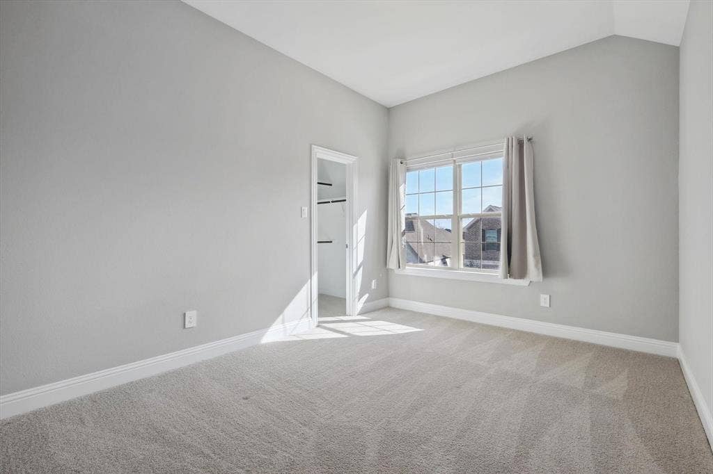 Bedroom featuring vaulted ceilings, plush carpet flooring, a multi-pane window, and a closet with shelving