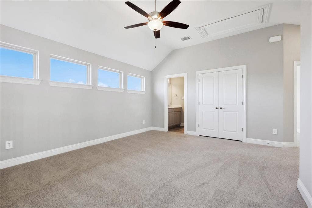 Expansive room featuring vaulted ceilings, a ceiling fan with integrated lighting, and light-toned carpeting