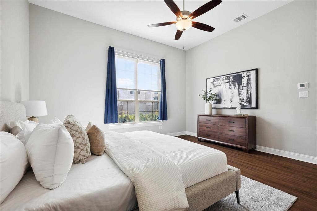 Spacious room featuring vaulted ceilings, wood-finish flooring, a ceiling fan with integrated lighting, and multiple windows