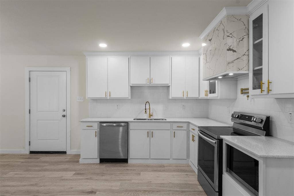 106 Mount Shasta Street, Dallas, TX 75211 Kitchen featuring white shaker cabinetry, light-toned countertops, tile backsplash, and wood-finish flooring