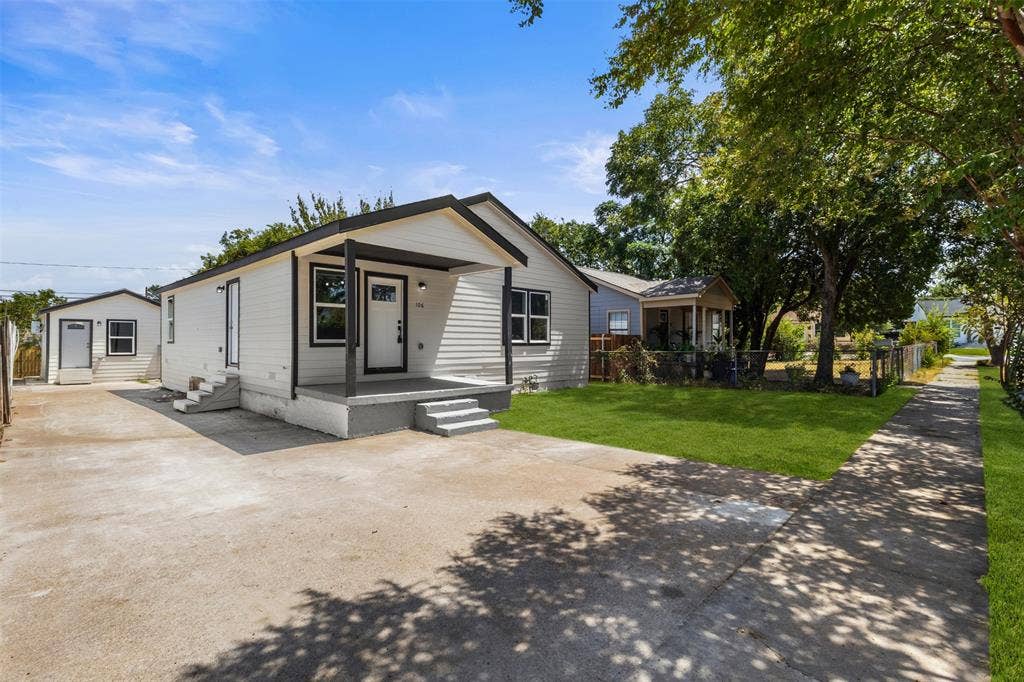 106 Mount Shasta Street, Dallas, TX 75211 White siding exterior with black trim, covered front porch, concrete driveway, and a separate structure