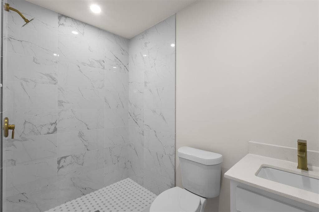 106 Mount Shasta Street, Dallas, TX 75211 Walk-in shower with large format tile, brushed gold fixtures, recessed lighting, white vanity with integrated sink, and white countertop