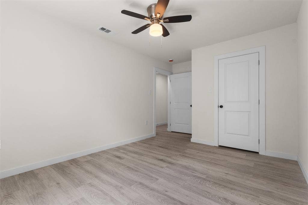 106 Mount Shasta Street, Dallas, TX 75211 Wood-finish flooring, white walls, two-panel interior doors, and a ceiling fan with integrated lighting