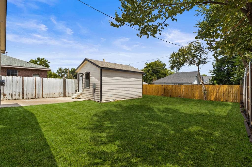 106 Mount Shasta Street, Dallas, TX 75211 Expansive lawn area with a separate outbuilding, a concrete pad, and wood fencing