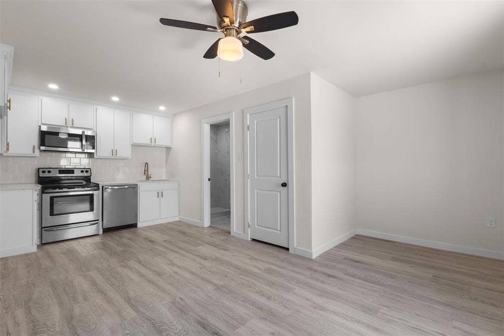 106 Mount Shasta Street, Dallas, TX 75211 White cabinetry with gold-finish hardware, stainless steel appliances, wood-finish flooring, recessed lighting, and a ceiling fan