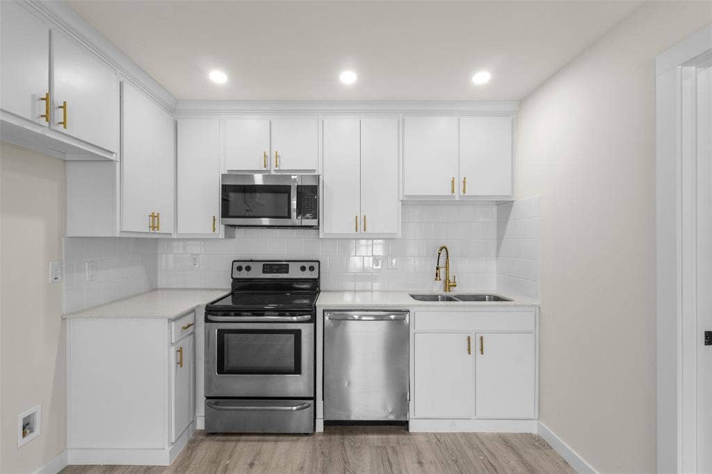 106 Mount Shasta Street, Dallas, TX 75211 Kitchen featuring white cabinetry, stainless steel appliances, a white tile backsplash, and wood-finish flooring