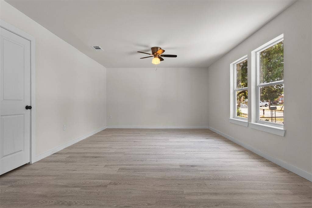 106 Mount Shasta Street, Dallas, TX 75211 Spacious room featuring wood-finish flooring, white painted walls, a ceiling fan with integrated lighting, and two double-hung windows