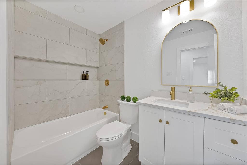 132 Yorkshire Drive, Cedar Hill, TX 75104 Bathroom featuring a white vanity with gold hardware, a white countertop, and an arched gold-framed mirror