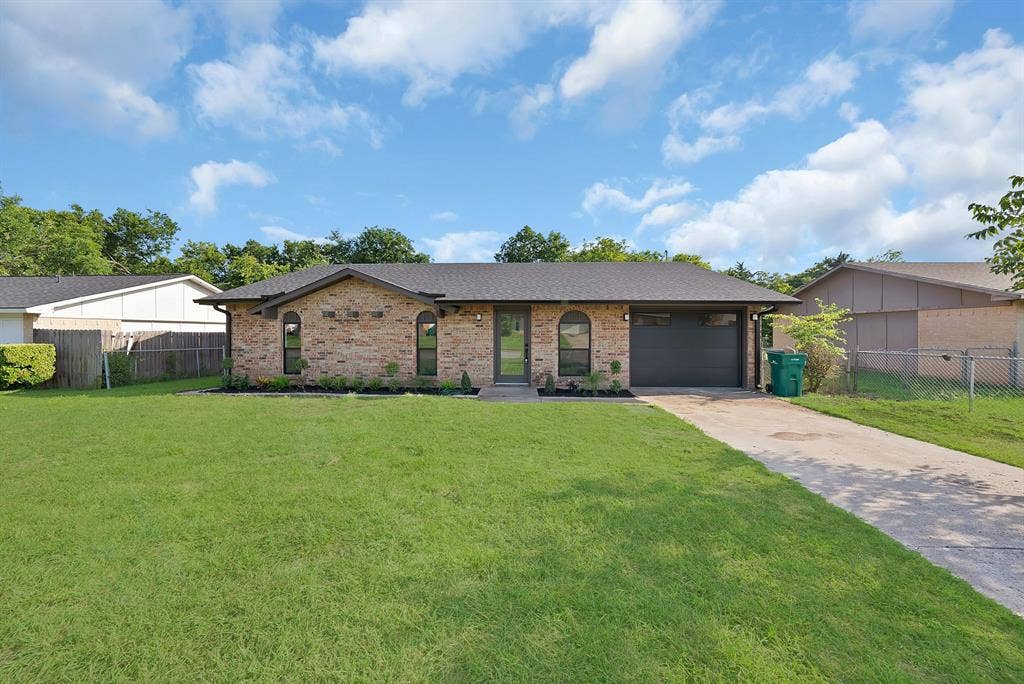 132 Yorkshire Drive, Cedar Hill, TX 75104 Brick facade residence featuring arched windows, a dark shingle roof, and a contemporary garage door
