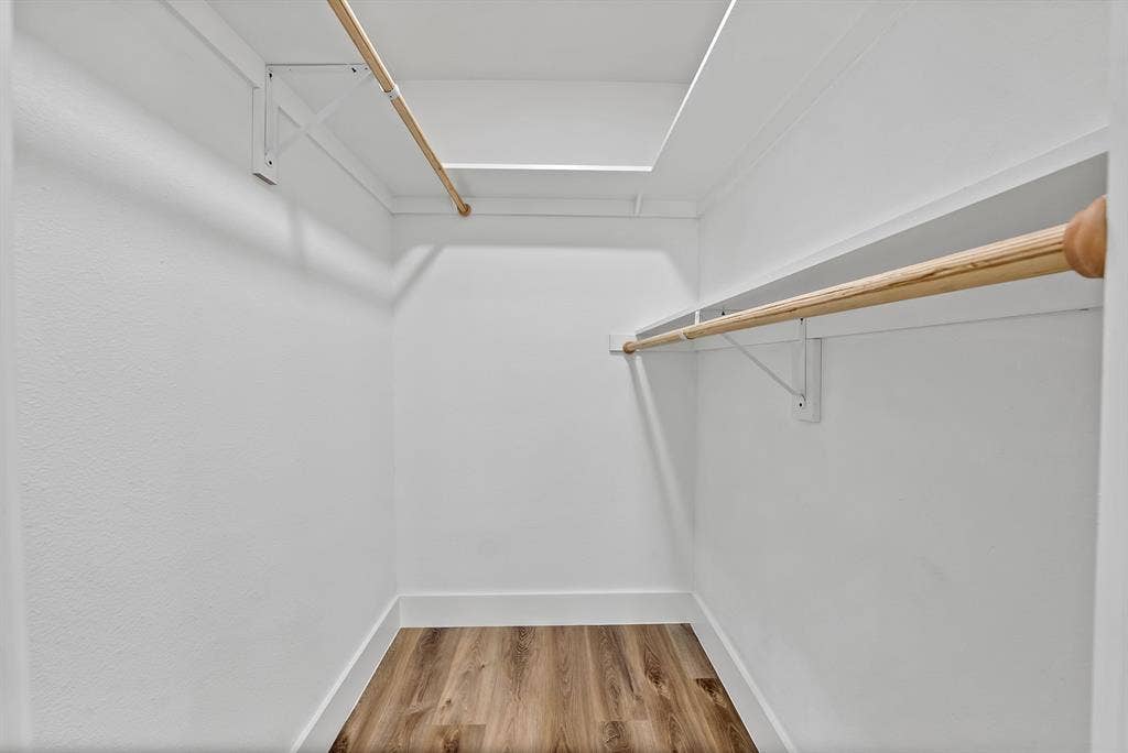 132 Yorkshire Drive, Cedar Hill, TX 75104 Walk-in closet featuring wood-finish flooring, white walls, white baseboards, a built-in shelf, and a wooden hanging rod