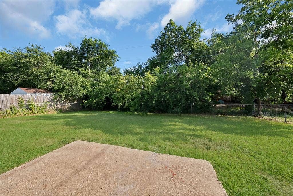 132 Yorkshire Drive, Cedar Hill, TX 75104 Expansive backyard featuring a concrete patio, mature trees, and a combination of wood and chain-link fencing