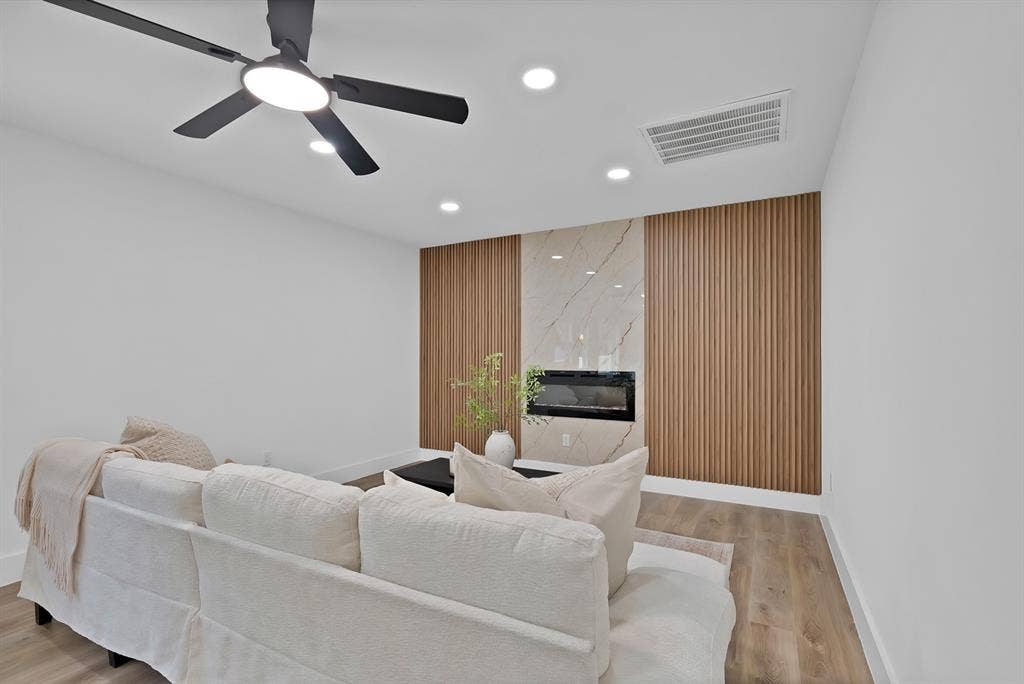 132 Yorkshire Drive, Cedar Hill, TX 75104 Living space featuring a contemporary fireplace with a stone-finish surround, flanked by vertical wood paneling