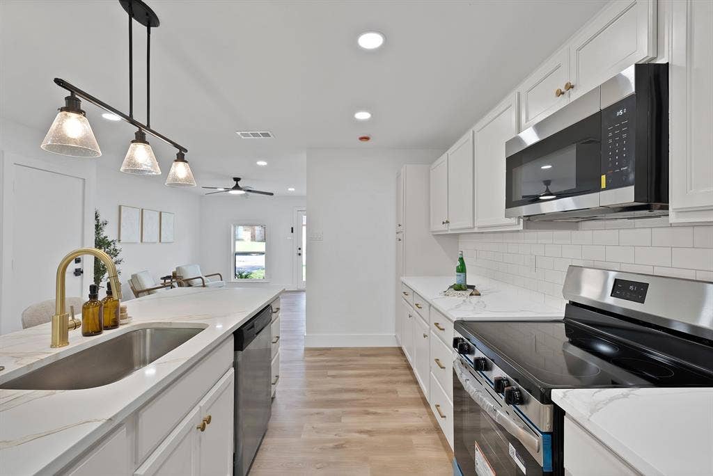 132 Yorkshire Drive, Cedar Hill, TX 75104 Contemporary kitchen featuring white cabinetry, light-toned countertops, subway tile backsplash, stainless steel appliances, and wood-finish flooring