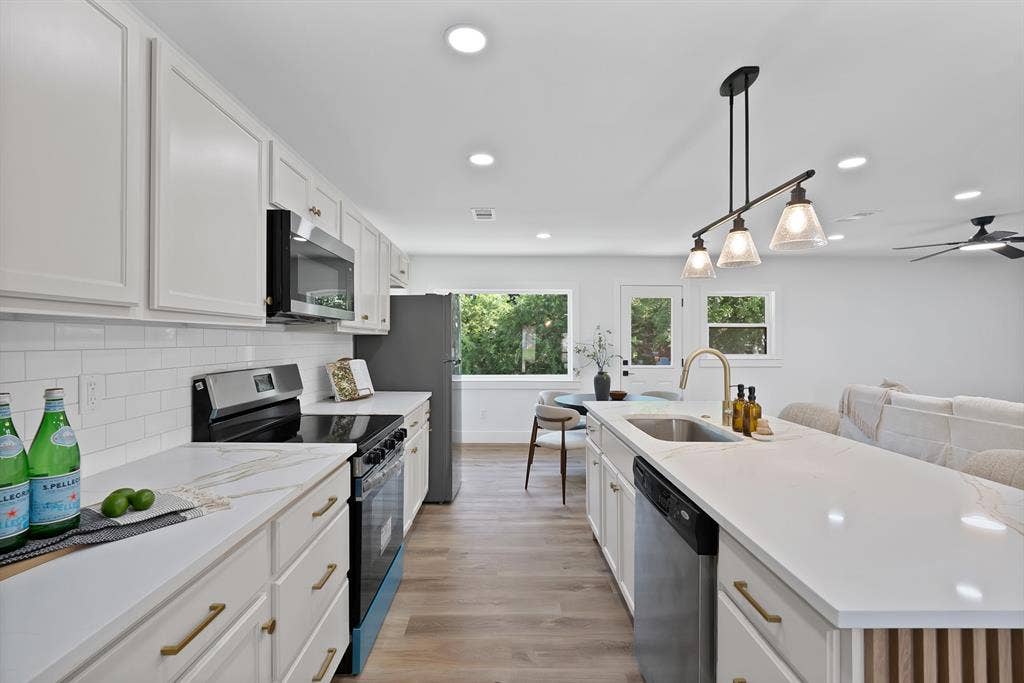132 Yorkshire Drive, Cedar Hill, TX 75104 Bright kitchen featuring white shaker cabinetry, light-toned countertops, a subway tile backsplash, stainless steel appliances, and wood-finish flooring