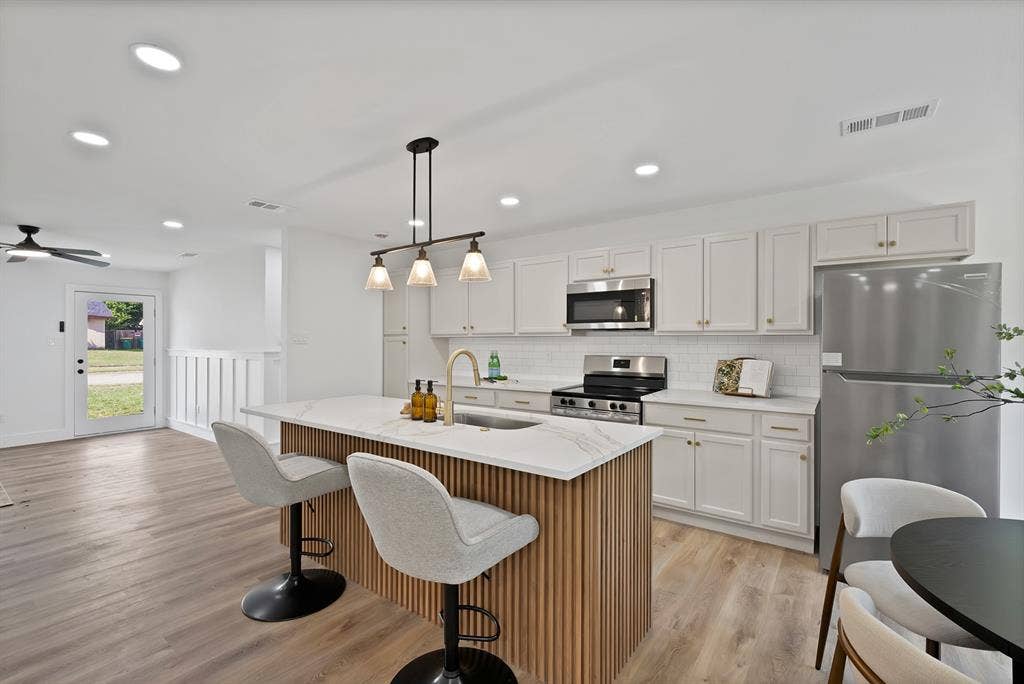 132 Yorkshire Drive, Cedar Hill, TX 75104 Modern kitchen featuring a central island with wood-finish paneling and a light-toned countertop, complete with a pendant light fixture