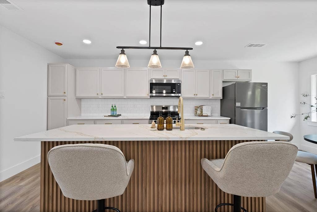 132 Yorkshire Drive, Cedar Hill, TX 75104 Kitchen featuring a substantial island with a patterned wood-finish base, light-toned countertop, and modern pendant lighting