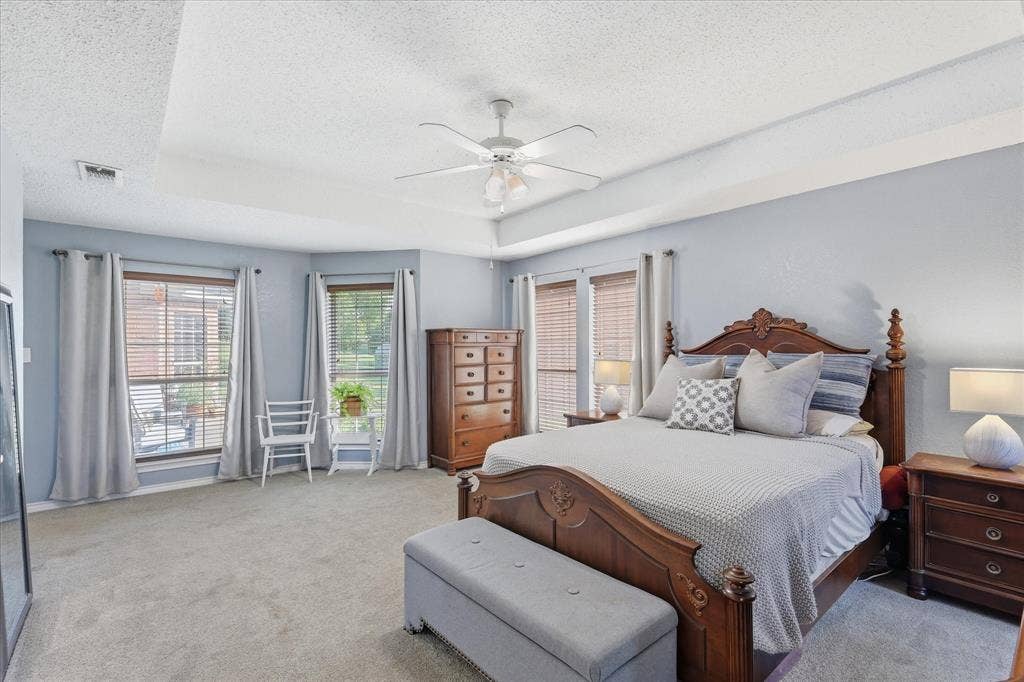 510 Saralvo Road, Midlothian, TX 76065 Spacious bedroom featuring a tray ceiling with a ceiling fan, plush carpet flooring, and two large windows with blinds and drapery