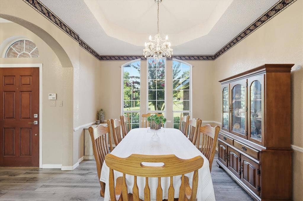 510 Saralvo Road, Midlothian, TX 76065 Formal dining area with large bay windows, a tray ceiling, and a crystal chandelier