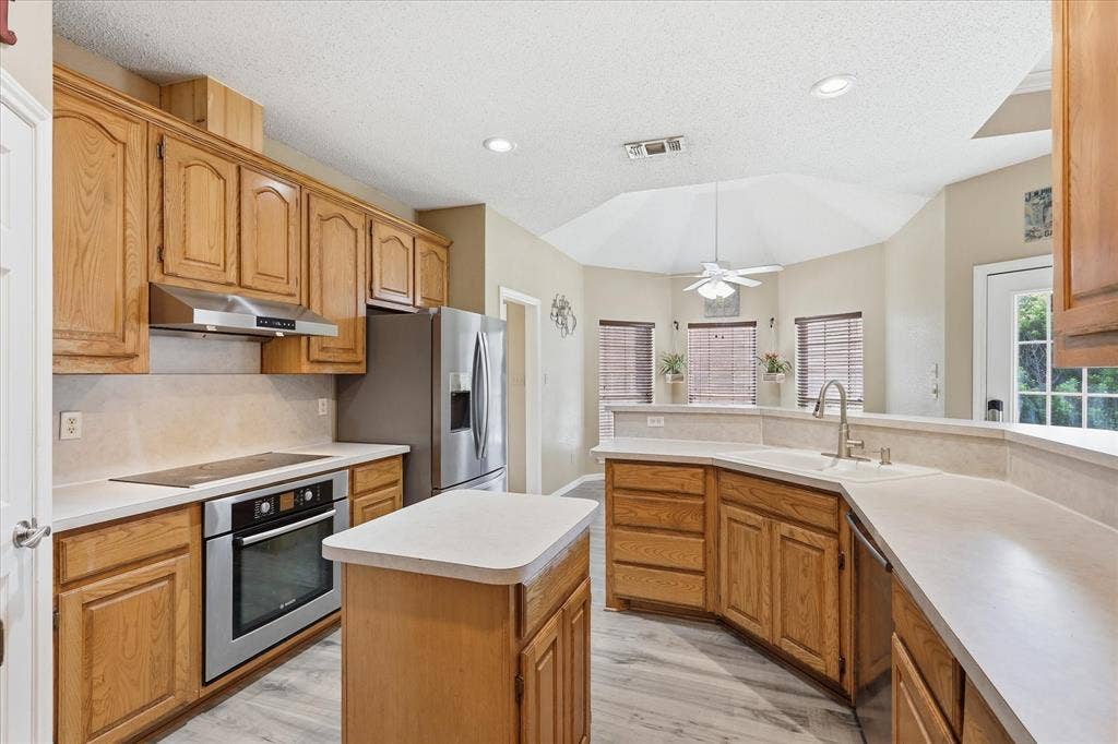 510 Saralvo Road, Midlothian, TX 76065 Well-appointed kitchen featuring light wood cabinetry, stainless steel appliances, a center island, light countertops, and wood-finish flooring