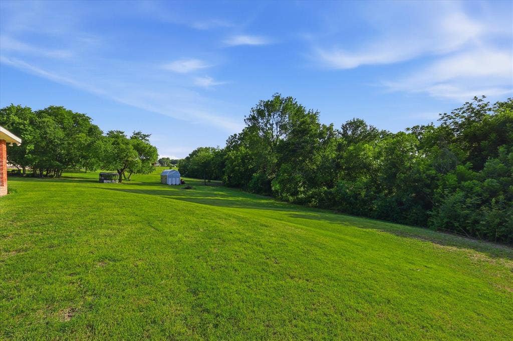 510 Saralvo Road, Midlothian, TX 76065 Expansive green lawn surrounded by mature trees, featuring a visible shed structure in the distance