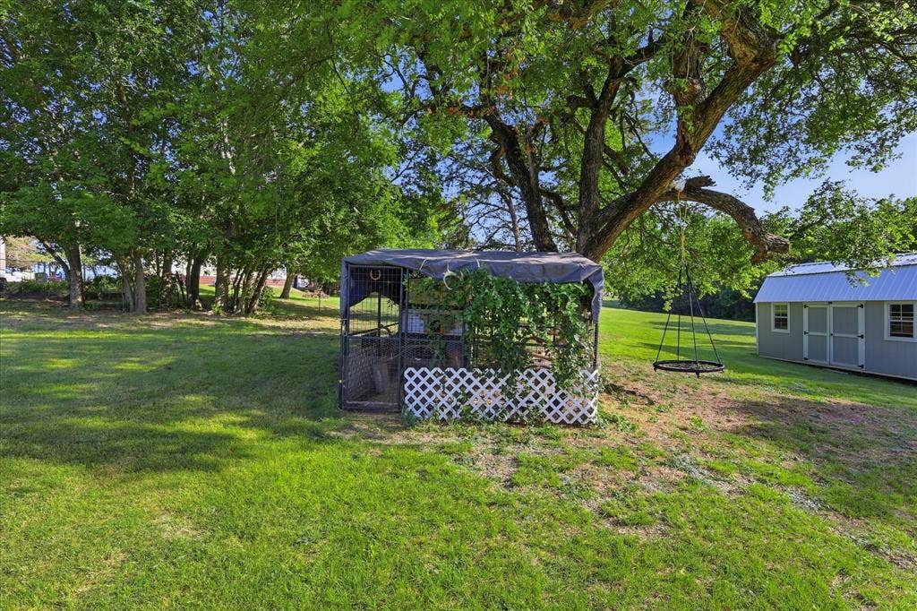 510 Saralvo Road, Midlothian, TX 76065 Expansive green lawn featuring mature trees, a detached storage shed with a metal roof, and a covered outdoor structure with lattice detailing