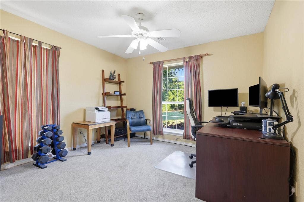 510 Saralvo Road, Midlothian, TX 76065 Carpeted room with a ceiling fan, two windows featuring drapes, and a built-in wooden ladder shelf