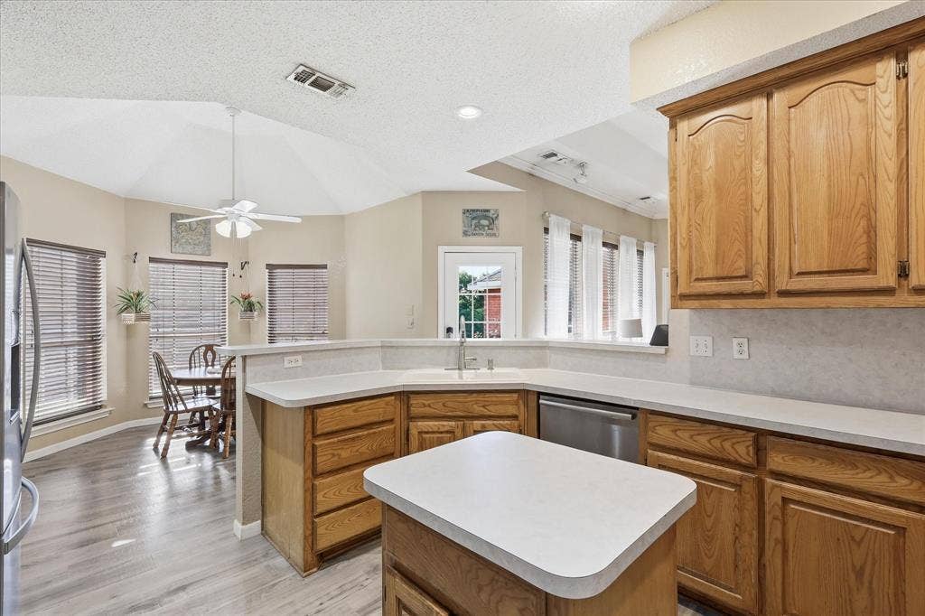 510 Saralvo Road, Midlothian, TX 76065 Kitchen featuring wood-finish cabinetry, white countertops, stainless steel dishwasher, and a central island
