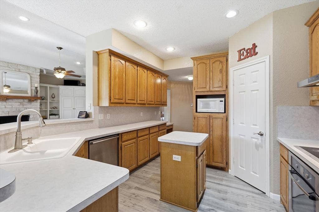 510 Saralvo Road, Midlothian, TX 76065 Kitchen featuring wood-finish cabinetry, solid surface countertops, a built-in microwave, and wood-finish flooring