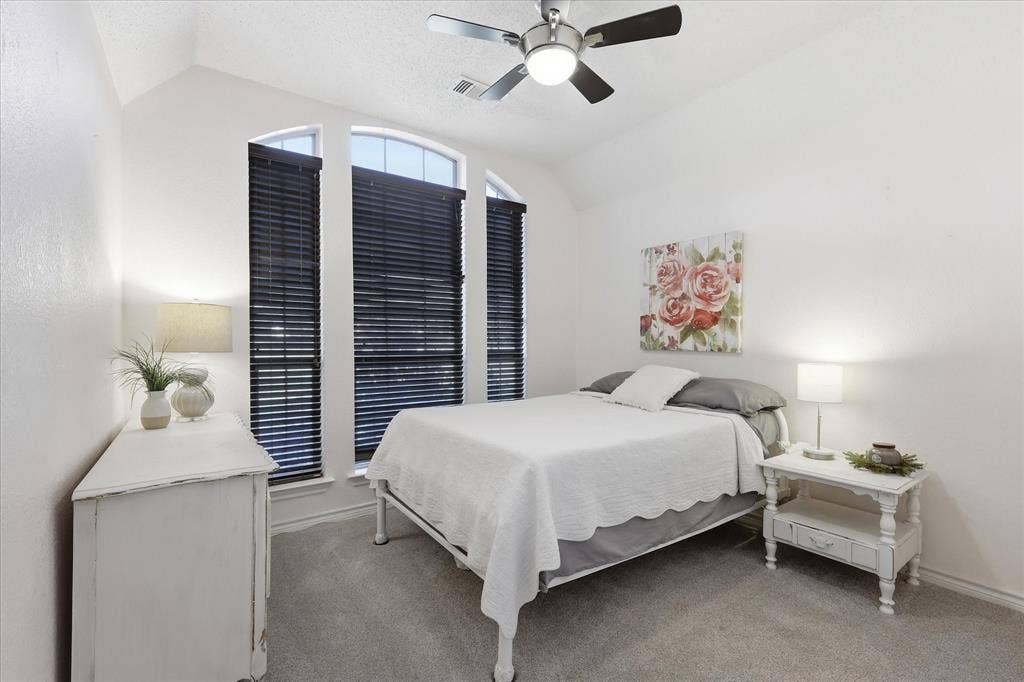 510 Saralvo Road, Midlothian, TX 76065 Room featuring vaulted ceiling, arched windows with dark horizontal blinds, and neutral carpet