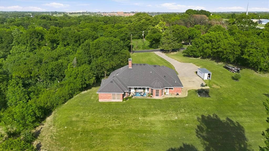 510 Saralvo Road, Midlothian, TX 76065 Expansive property featuring a brick exterior home with a dark shingle roof, surrounded by mature trees