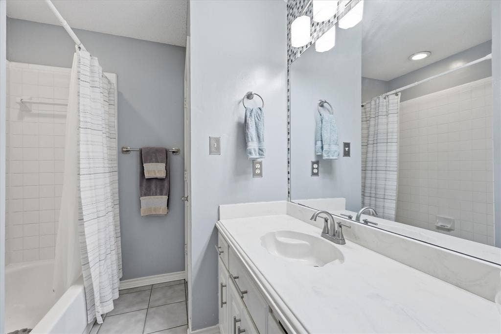 510 Saralvo Road, Midlothian, TX 76065 Bathroom vanity featuring a white countertop with an integrated sink, brushed nickel faucet, and a large mirror with overhead lighting