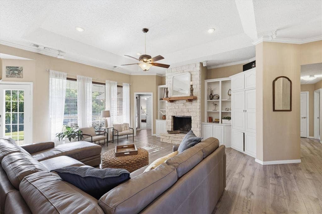 510 Saralvo Road, Midlothian, TX 76065 Spacious living area featuring a stone-clad fireplace with wood mantel, built-in cabinetry, wood-finish flooring, a ceiling fan, and multiple windows