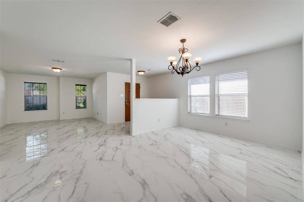 12841 Serenity Drive, Frisco, TX 75035 Open-concept interior featuring polished tile flooring with a marble-effect finish, a multi-light chandelier, and multiple windows with horizontal blinds