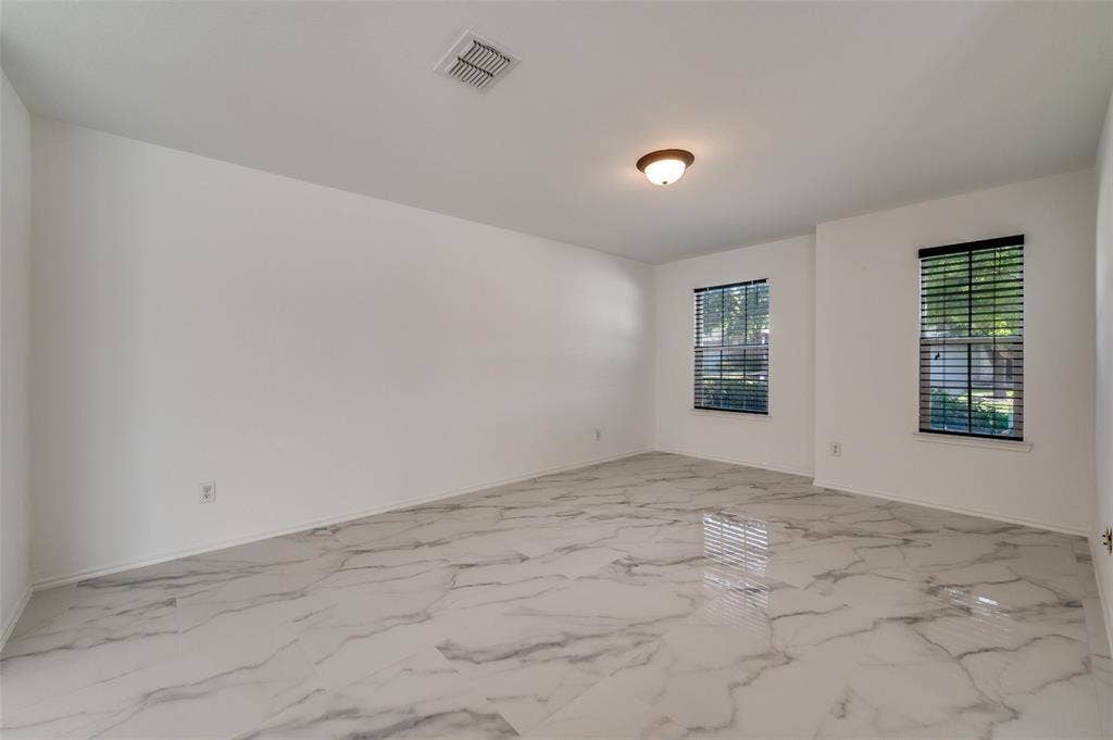 12841 Serenity Drive, Frisco, TX 75035 Spacious room featuring large format marble-look tile flooring, two windows with blinds, a ceiling-mounted light fixture, and white painted walls