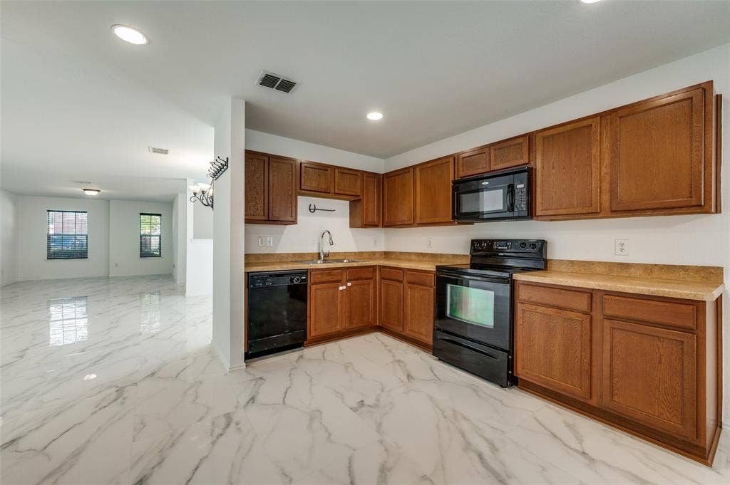 12841 Serenity Drive, Frisco, TX 75035 Kitchen featuring wood cabinetry, black appliances, light-toned countertops, and a white tile backsplash