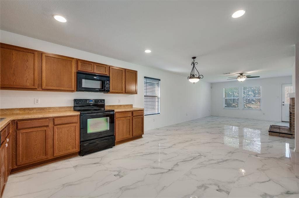 12841 Serenity Drive, Frisco, TX 75035 Contemporary kitchen featuring wood cabinetry, laminate countertops, and a black appliance suite with a microwave and range