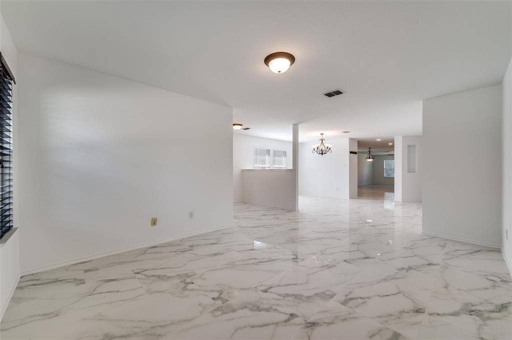 12841 Serenity Drive, Frisco, TX 75035 Spacious interior featuring marble-finish flooring throughout, a flush-mount ceiling light fixture, and horizontal window blinds