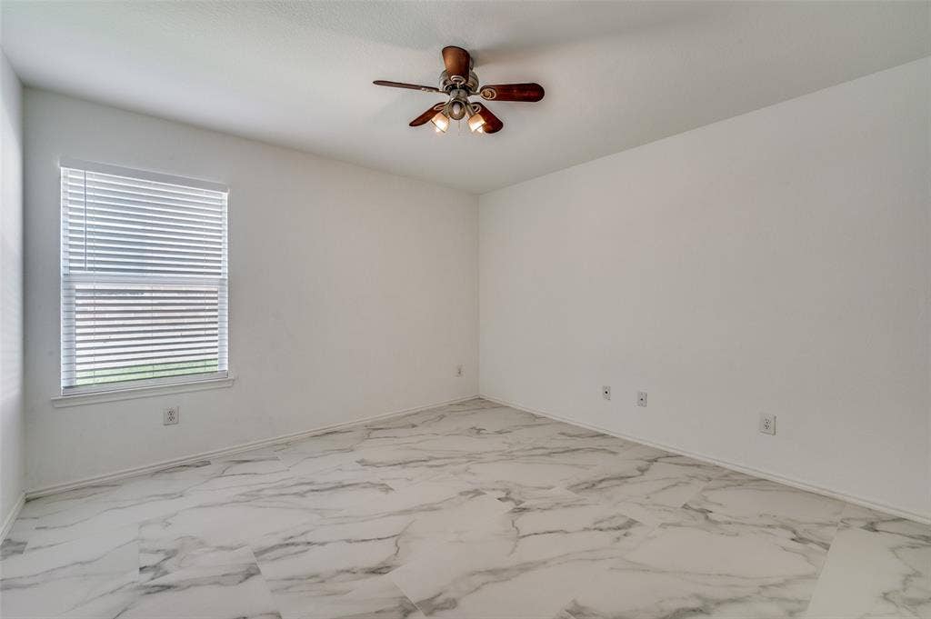 12841 Serenity Drive, Frisco, TX 75035 Spacious room featuring white walls, large window with blinds, and a wood-finish ceiling fan with integrated lighting