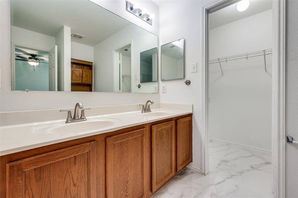 12841 Serenity Drive, Frisco, TX 75035 Bathroom vanity featuring a dual sink, wood-finish cabinetry, and a spacious counter
