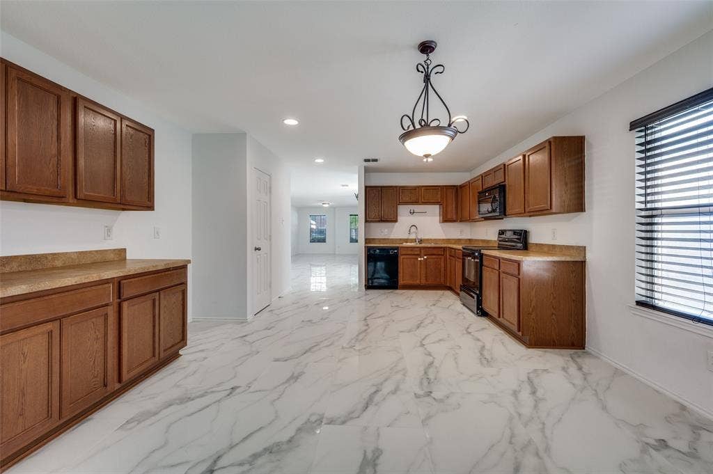 12841 Serenity Drive, Frisco, TX 75035 Kitchen featuring wood cabinetry, stone-finish countertops, black appliances, a window with blinds, and white marble-look flooring