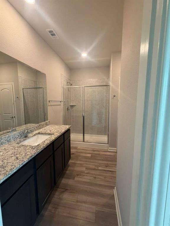 310 Foster Lane, Anna, TX 75409 Spacious bathroom featuring a double vanity with granite-style countertops, dark wood cabinetry, and a walk-in shower with a glass enclosure