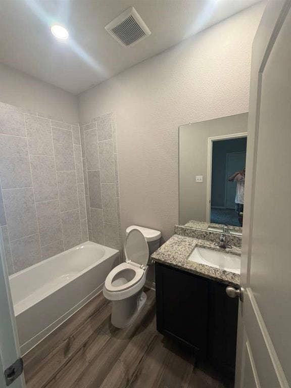 310 Foster Lane, Anna, TX 75409 Bathroom featuring a white bathtub, light gray subway tile surround, wood-finish flooring, and a single vanity with a granite countertop and dark cabinetry