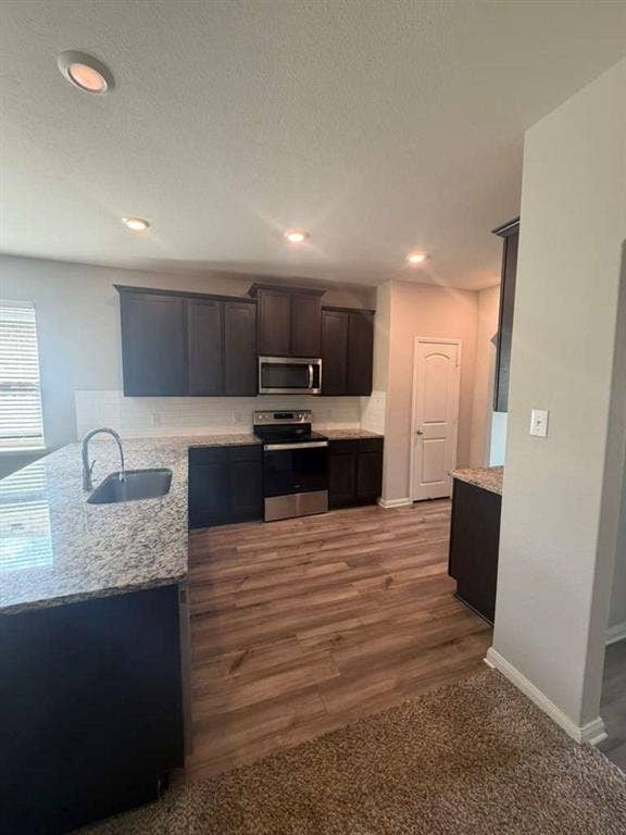 310 Foster Lane, Anna, TX 75409 Kitchen featuring dark wood-finish cabinetry, granite-style countertops, stainless steel appliances, and a subway tile backsplash