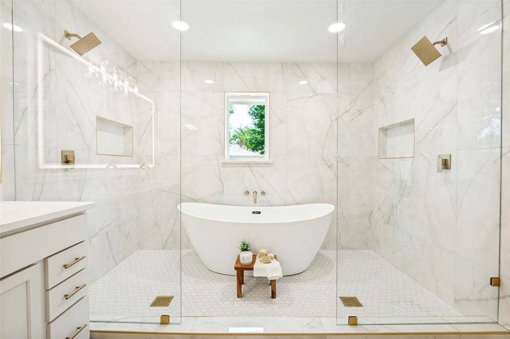 109 Shadow Drive, Red Oak, TX 75154 Freestanding soaking tub centered within an expansive wet room featuring a dual-head shower system with brass fixtures, marble-look wall tiling, and hexagonal floor tiles